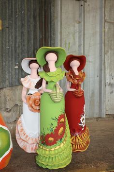 three colorfully painted vases sitting next to an orange and green apple on the ground