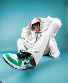 a man sitting on the ground wearing a white and green outfit