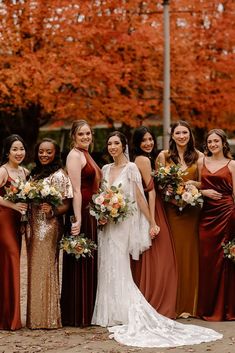 a group of women standing next to each other wearing dresses and holding bouquets in their hands