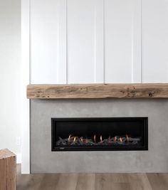 a fire place in the middle of a room with wood floors and white walls,