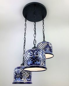 three hanging lights with blue and white designs on them, suspended from a ceiling fixture