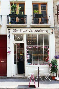 the outside of a bakery with tables and chairs on the sidewalk in front of it