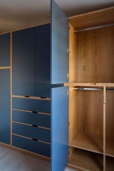 an empty closet with wooden shelves and blue drawers