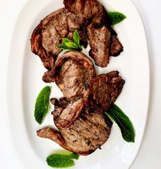 steaks with mint leaves on a white plate