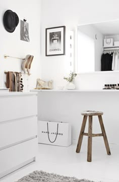 a white room with a stool, mirror and other items on the wall in front of it