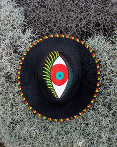 Hand painted straw hat in black, with acrylic colors (orange, green, yellow).  *The big eye on top of the hat, also known as the Greek eye or the «evil eye» , is a traditional symbol of protection from bad luck.  *The hat, also has small painted details around the brim's edges in orange, green, and yellow color.  Made in Greece 🇬🇷 with love ❤️  ☛ Crown Size: 57cm *Hand painted with high quality acrylic colors to protect the design from weather and water💦 Artisan Black Hat For Summer, Black Brimmed Sun Hat For Festivals, Traditional Black Summer Hats, Black Curved Brim Sun Hat For Festivals, Handmade Black Beach Hat, Handmade Black Straw Hat For Beach, Black Straw Hat With Short Brim For Festival, Traditional Black Beach Hat, Black Handmade Sun Hat With Curved Brim