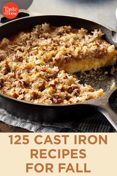 a cast iron skillet filled with food on top of a wooden table next to a cup of coffee