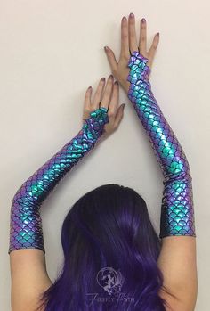 a woman with purple hair wearing blue and green mermaid fish scales on her arm sleeves