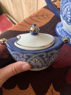 a hand holding a blue and white tea pot