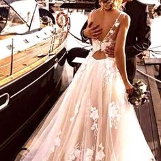 a woman in a wedding dress standing next to a man on a boat at the dock