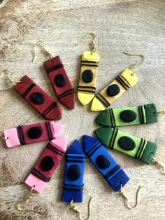 six pairs of colorful earrings sitting on top of a wooden table next to each other