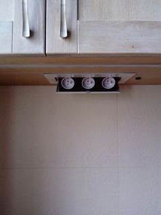 three white knobs mounted on the side of a kitchen cabinet above a stove top