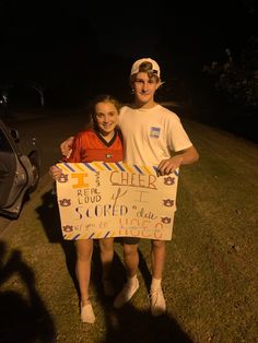 two people standing next to each other holding a sign that says cheer and it is written on it