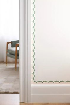 an open door with a green scalloped border on the side and a chair in the background