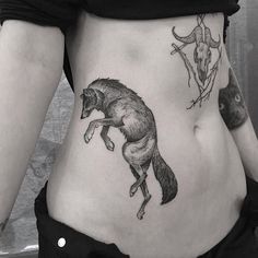 a black and white photo of a woman's stomach with an animal tattoo on it