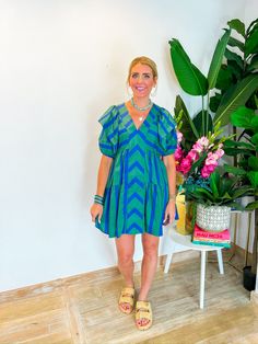 This playful mini dress combines blue and green in a charming chevron and stripe pattern, complete with a front panel and tiered ruffle seams. The ruffle sleeves and V-neckline add a touch of flirtiness, perfect for showing off your favorite necklaces. Whether you're heading to a weekend brunch or an outdoor concert, this dress has the perfect length for all heights. Style it with strappy sandals and a wide-brim hat for a chic, summery look! PRODUCT FIT - TRUE TO SIZE MODEL DETAILS - BRENNA IS A Green Tiered Dress For Vacation, Green Tiered Dress With Short Sleeves For Summer, Green Tiered Mini Dress For Summer, Green Tiered Vacation Dress, Green Mini Dress With Ruffle Sleeves For Spring, Green Tiered Mini Dress For Vacation, Green Tiered Mini Dress For Brunch, Green Summer Tiered Dress, Green Ruffle Sleeve Mini Dress For Spring