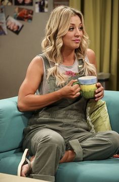 a woman sitting on top of a blue couch holding a cup