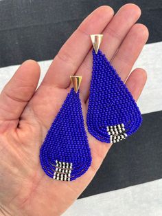 These fun, colorful, seed bead dangle earrings feature gorgeous cobalt blue seeds with a black and white patterned accent on the bottom fringe. They are made with size 11 miyuki seed beads. The closure is a gold plated stainless steel post with safety back. They hang approximately 3.0 inches from the lobe and measure 1.5" inches across their widest point.Each pair is made to order and handmade. Each earring takes several hours to complete as each bead is stitched together, one by one, using bead Blue Long Drop Jewelry With Beaded Fringe, Blue Dangle Jewelry With Black Beads, Bead Dangle Earrings, Steel Post, Beaded Dangle Earrings, Beaded Dangles, Seed Bead, Cobalt Blue, Bead Work