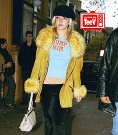 a woman walking down the street with a fur coat over her shoulders and handbag in her other hand