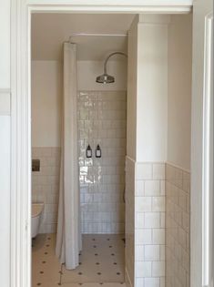 an open door leading to a bathroom with white tile and black accents on the walls