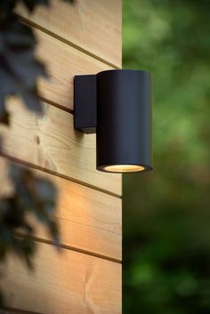 a black outdoor light on the side of a wooden wall