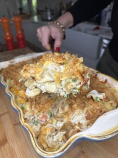 a person scooping food out of a casserole dish