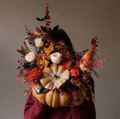 a woman is holding a pumpkin decorated with flowers