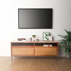 a flat screen tv mounted to the side of a wooden cabinet in a living room