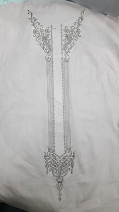 a white pillow with silver embroidered designs on it