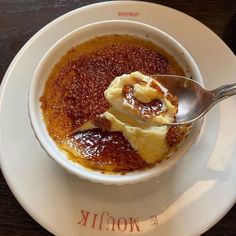 a white bowl filled with food on top of a wooden table next to a spoon