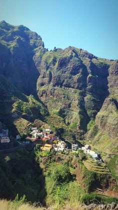 a mountain side town nestled in the middle of a valley surrounded by lush green mountains