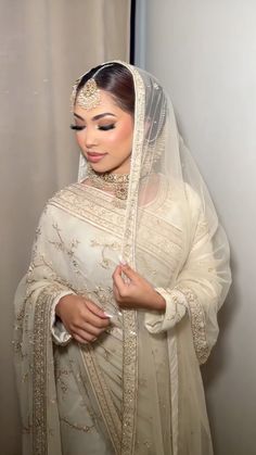 a woman wearing a white bridal gown and veil with her hands on her hips