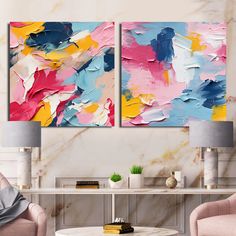 two paintings on the wall in a living room with pink chairs and a coffee table