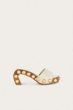 A sculptural mule, the elegant curved wood frame of the Devora Sandal creates an eye-catching play of negative space. Moire textured brass metal studs adorn the architectural wood frame and are balanced by the Off White-hued napa leather strap. Unique Heels, Woven Leather Sandals, Clear Shoes, Luxury Designer Shoes, Curved Wood, Bike Shoes, Studded Sandals, Cult Gaia, Unique Shoes