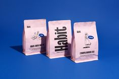 three bags of coffee sitting next to each other on a blue surface with white writing