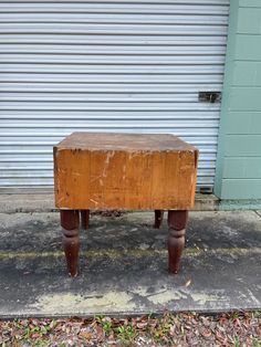 an old wooden stool sitting on the side of a road next to a garage door