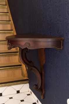 a wooden shelf sitting on the side of a blue wall next to a stair case