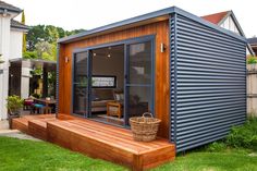 a small house made out of shipping containers in the grass with a deck and picnic table