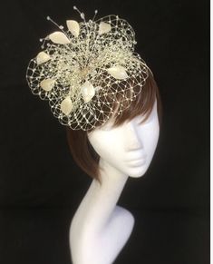 Gold and cream leaf fascinator perfect for the guest who wants something fairly understated. This design is a beautiful selection of glass effect leaves and flowers clustered together amongst a fine layer of veiling and set onto a fine comfort base tiara band. As with all our designs, this piece can be made exact to the image or in any colour combination to match in with your outfit. If a specific colour is required customers can message over an image of their outfit and accessories, or if time Elegant Beige Headpiece For Party, Beige Mini Hat Headband For Weddings, Elegant Beige Headpiece For Events, Elegant Handmade Flowers Headpiece For Events, Elegant Headpieces With Handmade Flowers For Events, Elegant Headband With Handmade Flowers For Party, Elegant Party Headband With Handmade Flowers, Beige Wedding Headband, Elegant Headband For Wedding Guests