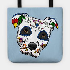 a white dog with blue day of the dead sugar skull on it's face