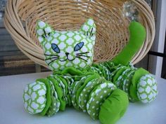 a green and white cat stuffed animal sitting on top of a table next to a wicker basket