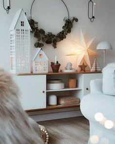 a living room with white furniture and christmas decorations on the wall, including a wreath