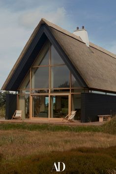 a large black building with a thatched roof and two lawn chairs in front of it