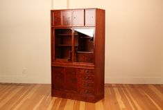 a wooden bookcase with drawers on top of it in the corner of a room