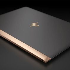 an open laptop computer sitting on top of a black surface with gold trimmings