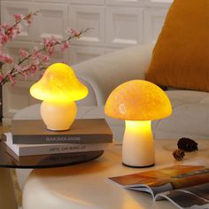 two mushroom shaped lights sitting on top of a table next to books and a vase with flowers