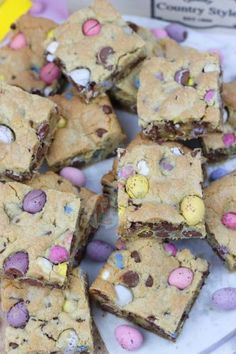 a white plate topped with chocolate chip cookie bars covered in easter eggs and m & ms