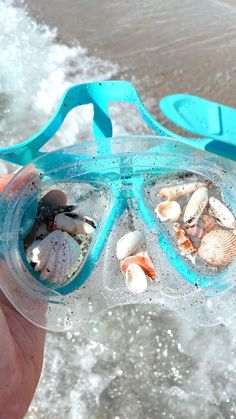 a person holding up a goggles with shells in it