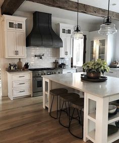 a kitchen with white cabinets and an island in the middle, surrounded by stools