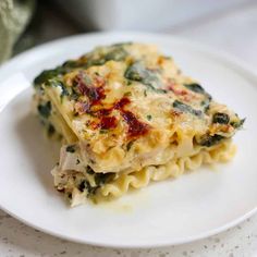 a white plate topped with lasagna covered in cheese and spinach